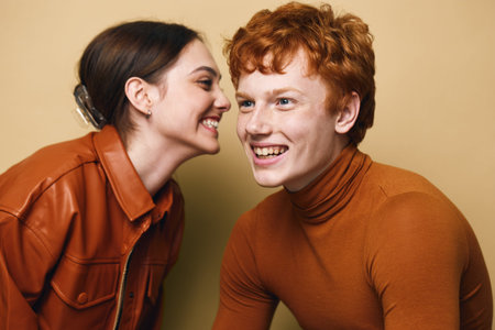 Young woman and man smiling with joy and friendship in casual autumn clothing. Closeup portrait of cheerful people enjoying conversation in warm studio environment.の写真素材