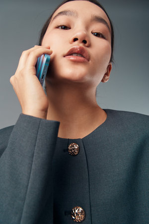 Woman talking on smartphone with serious expression closeup portrait. Female model in dark jacket...
