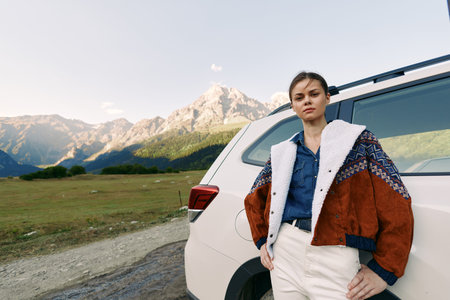 Woman, car, mountains, travel, jacket, portrait. Young woman leaning against a white SUV on a...