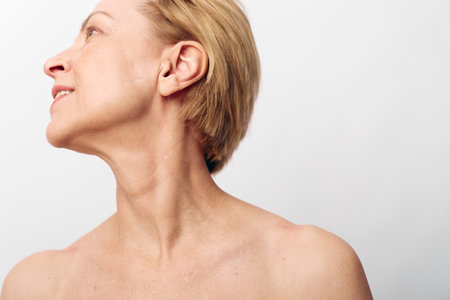 Portrait of a mature woman with short hair turning her head to the side, showing neck and shoulder...