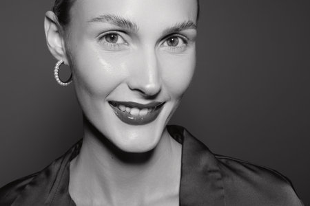 Close up portrait of smiling woman with hoop earrings in studio, natural beauty and confident look.