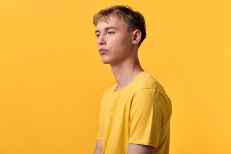 Male wearing a yellow tee stands before a solid yellow backdrop, creating a bold monochrome look...