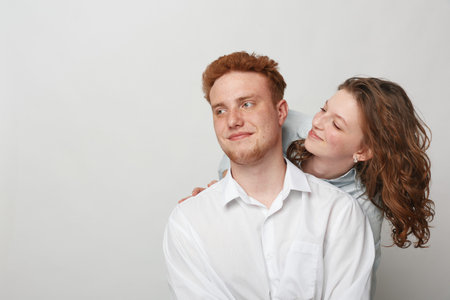 Young couple with red hair and curly hair in casual clothes smiling and looking at each other on...