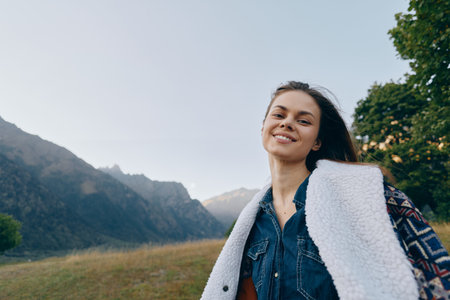 Woman smiling portrait in mountains and nature outdoors, happy traveler wearing denim and shearling...