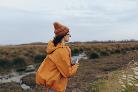 Woman lifestyle concept with a young woman wearing an orange jacket and brown hat standing outdoors...
