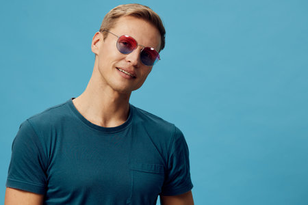 Casual smiling man wearing sunglasses and teal t-shirt looking at camera with a friendly expression...