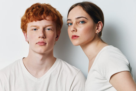 Portrait of young man and woman with serious expressions in white shirts against plain background. Closeup of teenagers with natural skin and casual hairstyle posing indoors.の写真素材