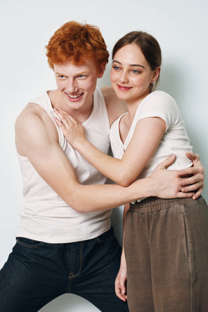 Couple smiling and hugging in casual clothes against white background. Young man and woman with...