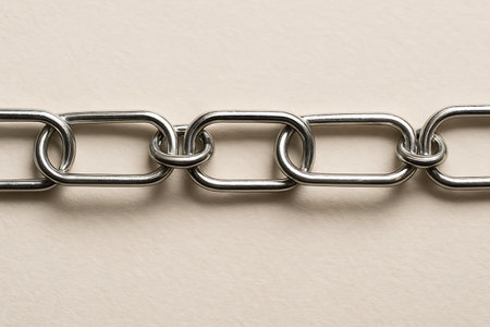 Closeup of metal chain on a white textured paper background.の素材
