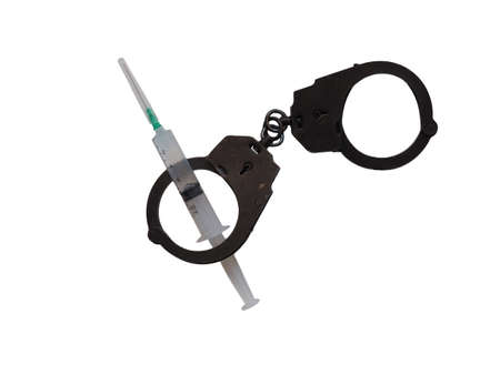 Instrument of crime. Medical syringe in handcuffs on a white background.の写真素材