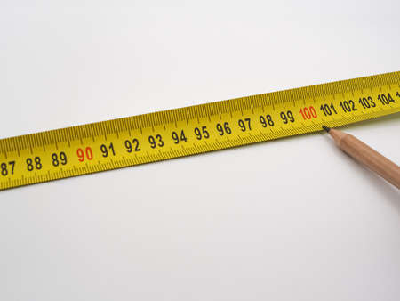 Construction tape measure and pencil on a white background. the figure of a hundredの写真素材