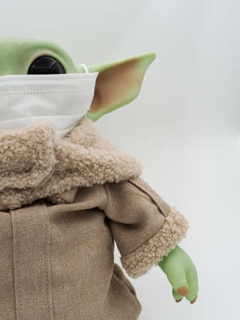 Unknown green baby alien in a medical mask on a light backgroundの写真素材
