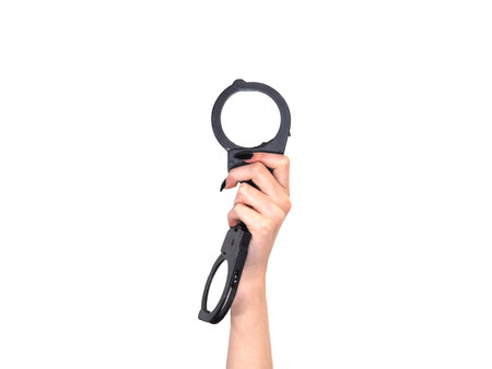Female hand with police handcuffs isolated on white background. The concept of crime and punishment. Feminism, equality.の写真素材