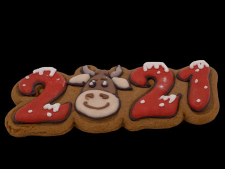 Christmas gingerbread on a black background. Figures 2021 with a bull. Brown homemade cookies in colored icing sugar. New year ornament handmade decoration.の写真素材