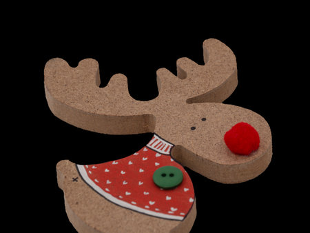 Traditional Christmas deer. Handmade pressed wood figurine in a red sweater with hearts. Handmade on a black background.の写真素材