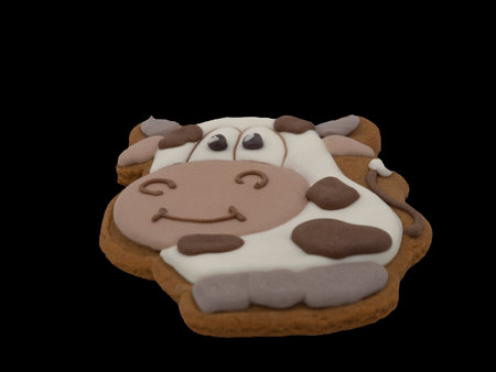 Christmas gingerbread on a black background. The cow is the symbol of the year. Brown homemade cookies in colored icing sugar. New year ornament handmade decoration.の写真素材
