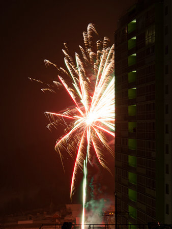 New Year or Christmas salute in the Russian suburbs. A smoking man on the balcony of a high-rise building, a skyscraper looks at the fireworks.の写真素材