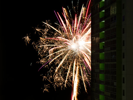New Year or Christmas salute in the Russian suburbs. A smoking man on the balcony of a high-rise building, a skyscraper looks at the fireworks.の写真素材