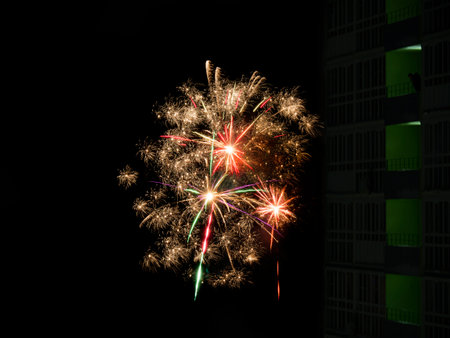 New Year or Christmas salute in the Russian suburbs. A smoking man on the balcony of a high-rise building, a skyscraper looks at the fireworks.の写真素材