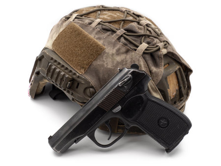 A modern army tactical helmet in camouflage with a Russian police black 9mm pistol. The concept of arming bandits, drug cartels, and insurgents. The photo is isolated on a white background.の写真素材