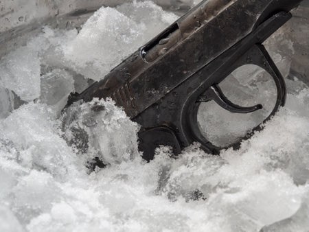 Police 9mm pistol frozen in a bucket with crushed ice cubes.の写真素材
