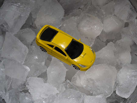 A toy mini model of a yellow car in a metal bar bucket with ice cubes. Abstract concept of drunk driving, a auto instead of a bottle of alcohol.の写真素材