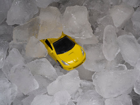 A toy mini model of a yellow car in a metal bar bucket with ice cubes. Abstract concept of drunk driving, a auto instead of a bottle of alcohol.の写真素材