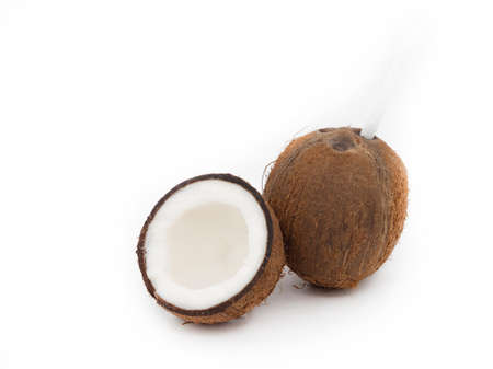 Exotic whole coconut isolated on a white background next to half of the fruit.の写真素材