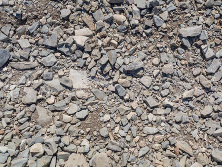 The texture of uneven roughly split gray small stones in close-up. The background of rubble in full screen.の写真素材
