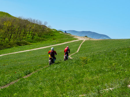 Novorossiysk, Krasnodar Territory, Russian Federation-07.11.2021: A biker on a pit bike (motorcycle) goes down a mountain with green grass during enduro training.のeditorial素材