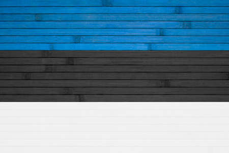 The national state flag of Estonia painted on the background of a wooden wall made of bamboo.