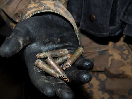 Spent cartridges in the hand of a military man. A special forces soldier shows physical evidence in the palm of his hand with a black glove. The concept of crime investigation.の写真素材