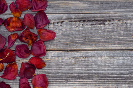 A frame of red dried rose petals on a gray wooden background. The concept of aromatherapy.の写真素材