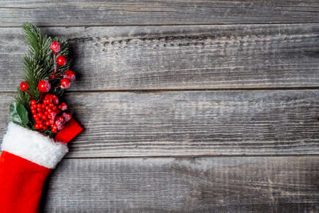 A branch of a decorated fir tree in a red white Christmas sock on a gray textured wooden background with copy space.の写真素材