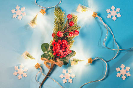Christmas flat lay with a garland of bottles, a green fir branch with decorations and white snowflakes on a blue background.の写真素材