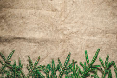 Merry Christmas background with green fir branches. Frame of Christmas tree branches on burlap. Copyspace for text or objects.の写真素材