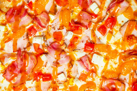 The texture of pizza with tangerines, chicken and bacon close-up. Festive Christmas food, unhealthy eating.の写真素材