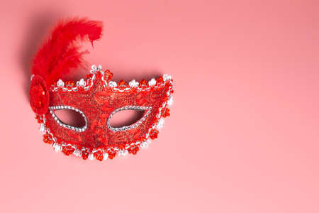 Traditional luxurious Italian red female mask on a pink background. A Venetian elegance masquerade...