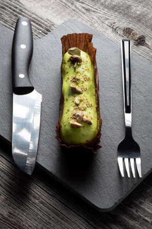 Dessert covered with green glaze on a slate black board with a serving fork and knife. Decorated...