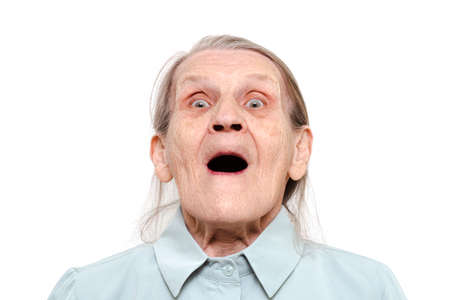 Lifestyle portrait of an elderly woman with an open mouth on a white background. Grandma looks at...