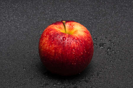 Washed red apple with water drops on a black background close up.の写真素材