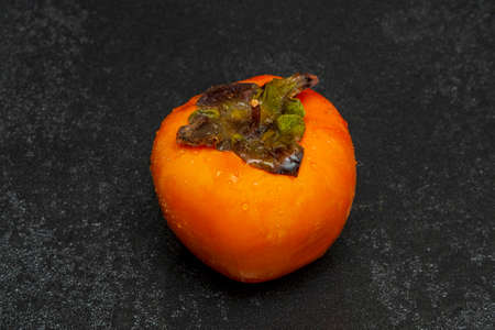 Washed persimmon with water drops on a black background close-up. exotic fruit.の写真素材