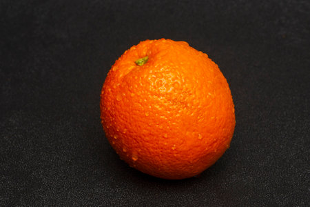 Washed orange fruit with water drops on a black background.の写真素材