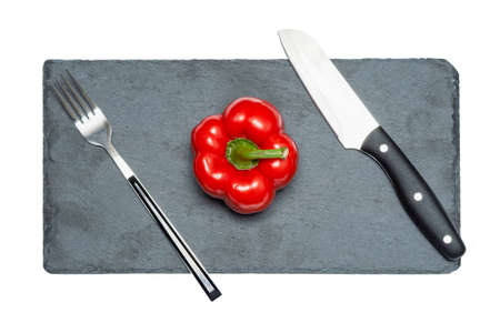 Red bell pepper with fork and knife black slate board. The concept of diet, food preparation.の写真素材