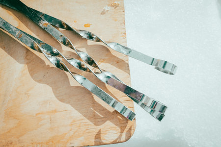 4 empty skewers lie on a wooden cutting board against the background of winter snow in the rays of the spring sun. The concept of a weekend picnic.の写真素材
