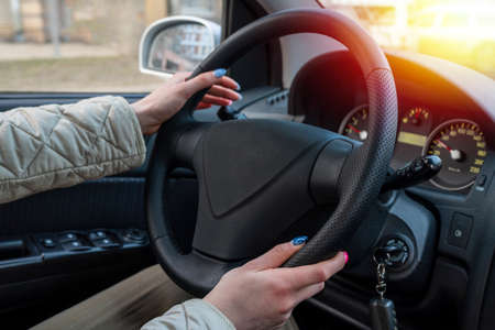 Business woman driving with a beautiful manicure. A confident girl holds the steering wheel with...