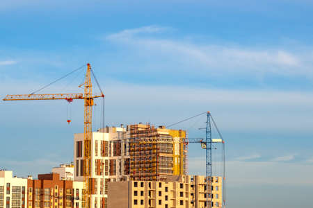 Construction of a new district of the city. Crane and high rise buildings on the background of blue...