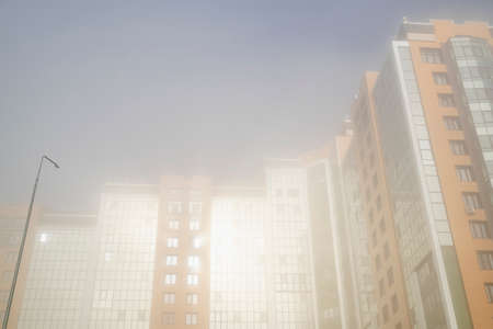 Multi storey residential buildings in the morning fog and the rays of the dawn sun.の写真素材