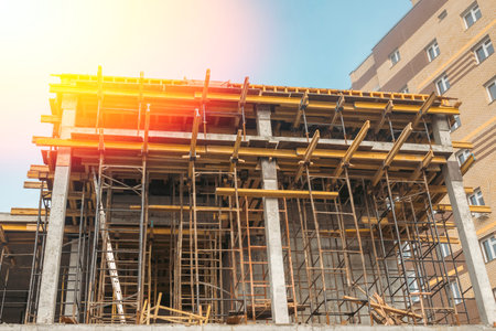 Scaffolding on the construction site, bottom view. The frame of the facade of a building under construction in close-up. The concept of growth and development of the city's infrastructure.の写真素材