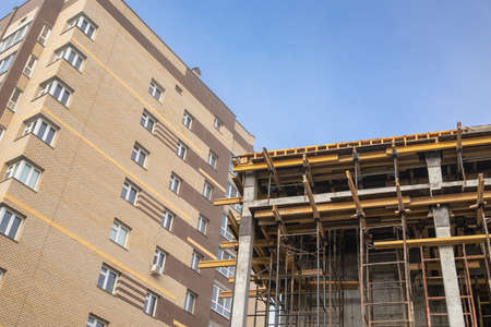 Scaffolding on the construction site, bottom view. The frame of the facade of a building under construction in close-up. The concept of growth and development of the city's infrastructure.の写真素材